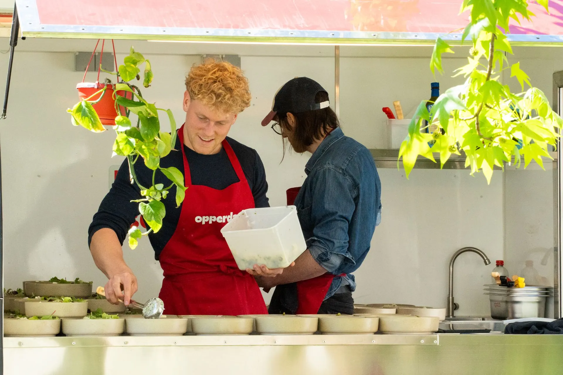 Le chef Elias Nys et un collègue dressent des assiettes dans la cuisine du food truck Opperdash