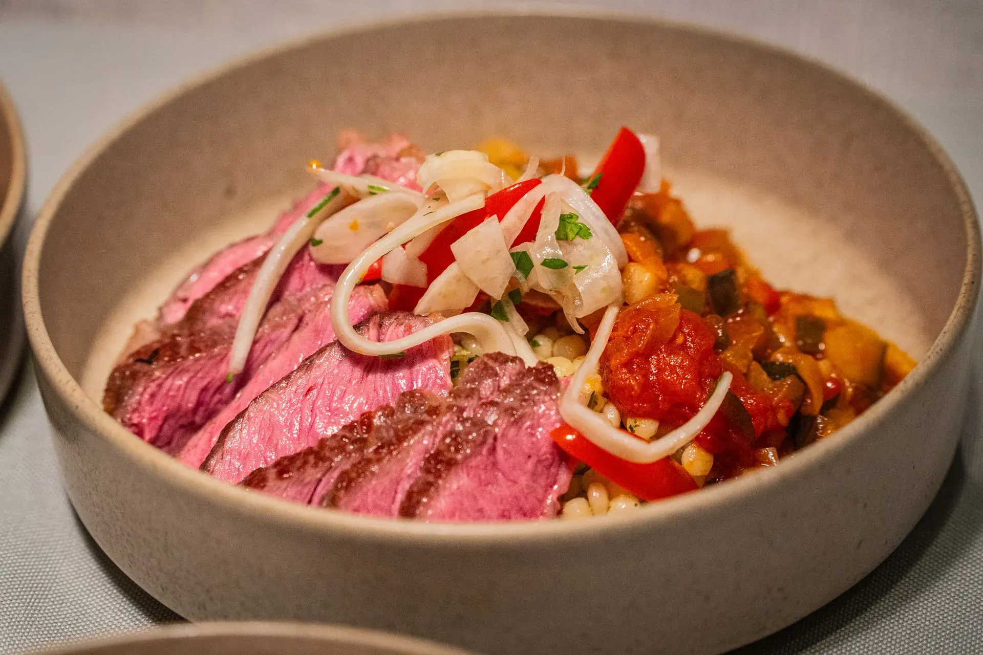 Bœuf tranché, poivrons rôtis et herbes sur une assiette en céramique